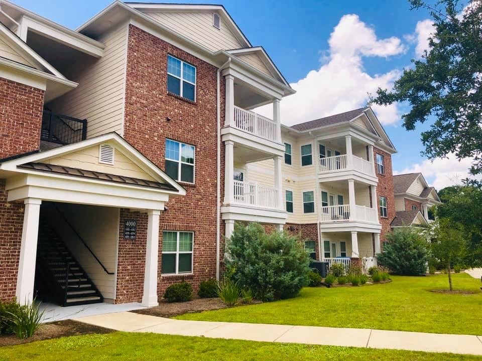 a brick apartment building with a lawn and a staircase