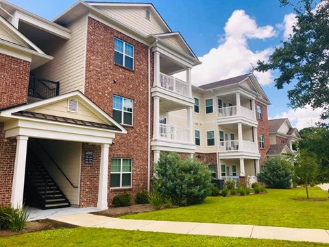 a brick apartment building with a lawn and a staircase