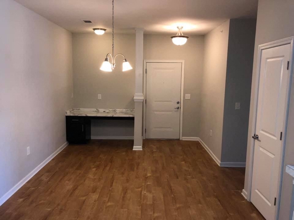 an empty living room with a wooden floor and a white door