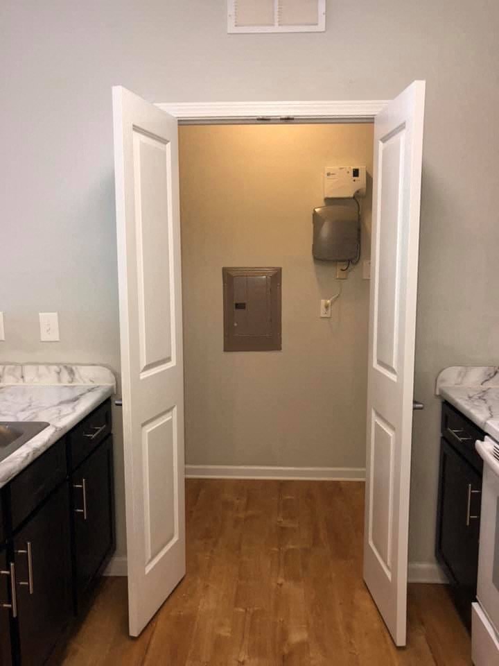 an empty kitchen with a door open to a room with a television