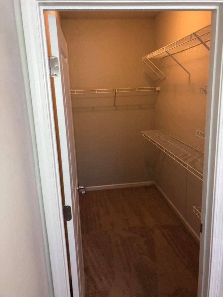 a walk in closet with empty shelves and a door