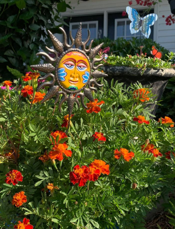 a sun statue in a garden with flowers