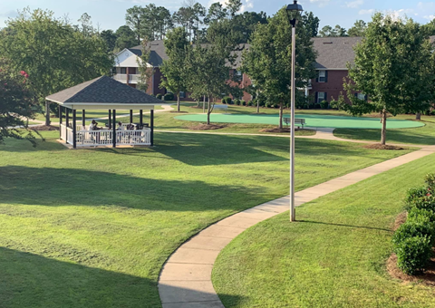 a gazebo in the middle of a park with a sidewalk