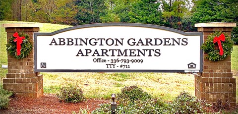 a sign for abington gardens apartments in front of trees