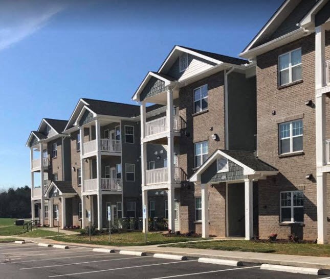 an apartment building with a parking lot in front of it