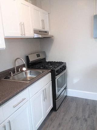 A kitchen with a black stove top oven and white cabinets.