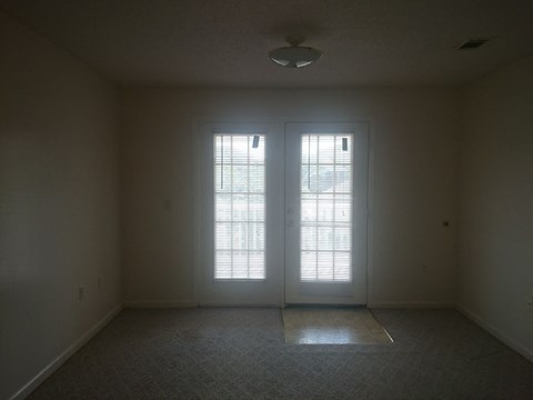 an empty living room with two doors and a window