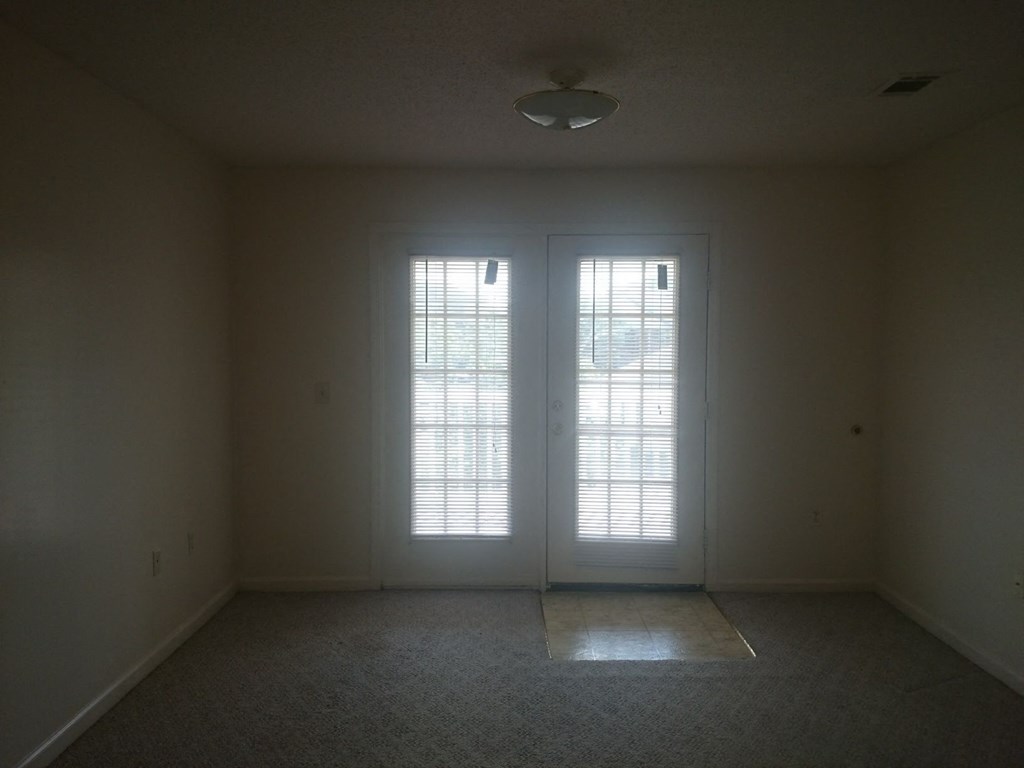 an empty living room with two doors and a window