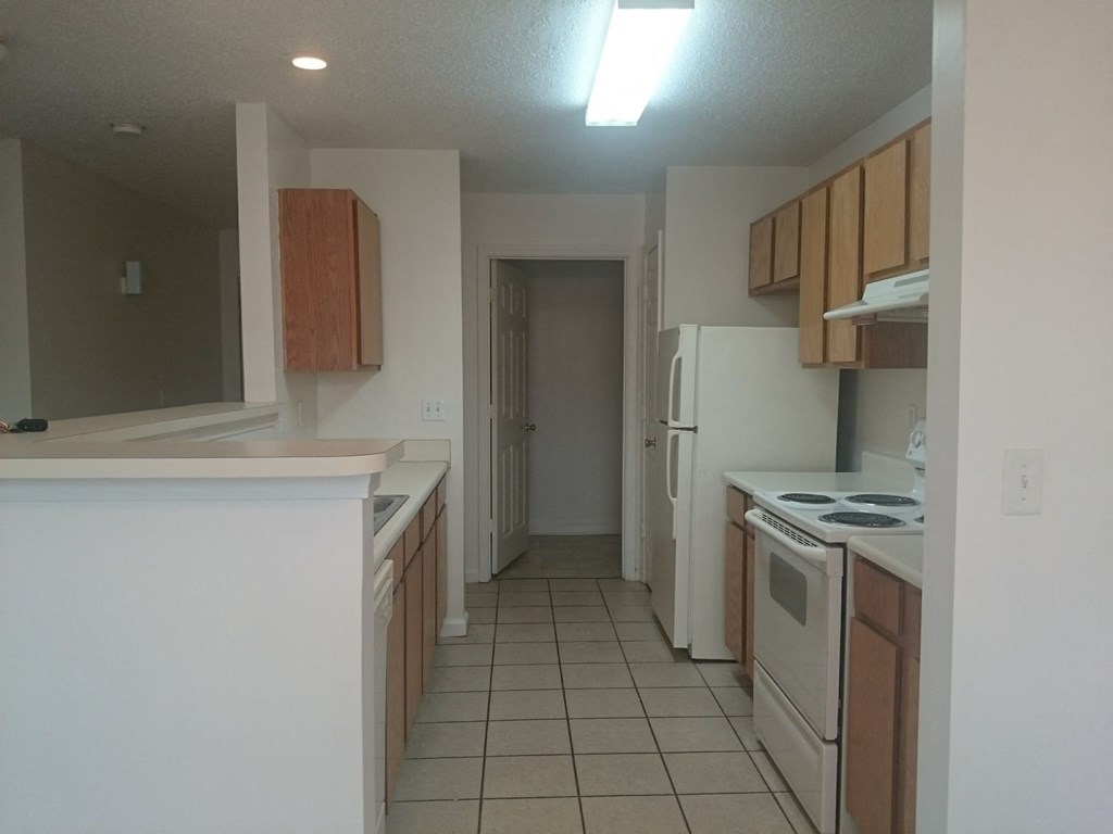 an empty kitchen with white appliances and wooden cabinets