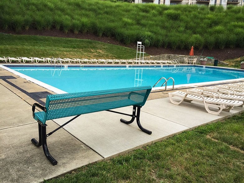 a park bench sitting next to a swimming pool