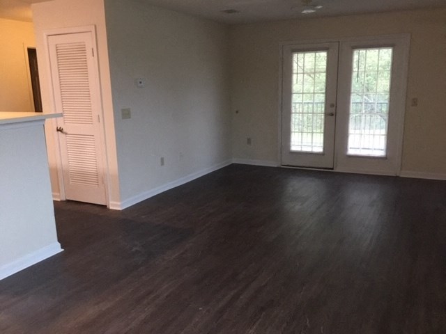 an empty living room with wooden floors and white doors