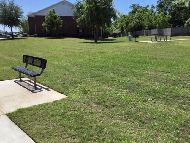 a park bench sitting in the grass in front of a building