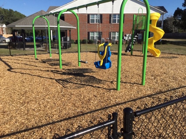a playground with a slide and monkey bars in front of a house