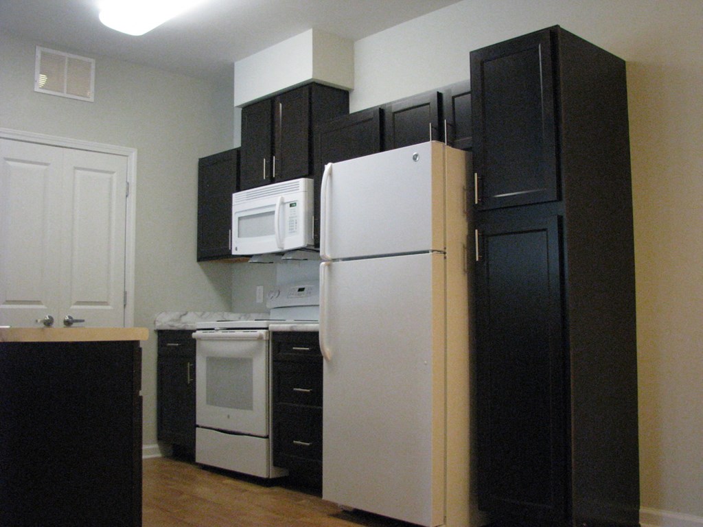 a kitchen with black cabinets and white appliances and a refrigerator