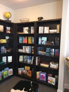 a black and white cat laying on the floor in front of a book shelf