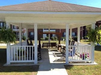 a porch with a white railing and a pavilion with chairs