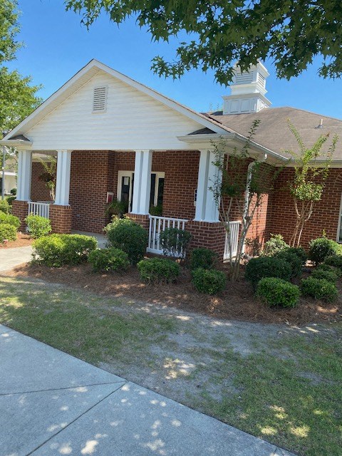 a small brick house with a porch and a sidewalk
