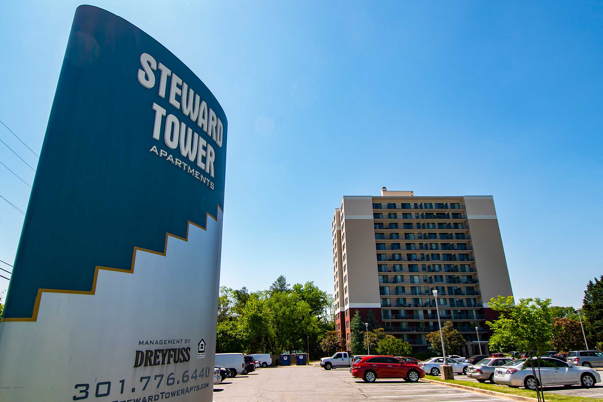 a sign in front of a parking lot with a tall building