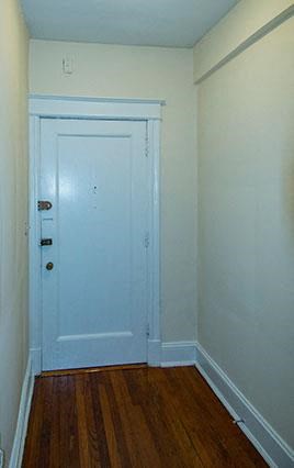 A white door is in a room with a wooden floor.