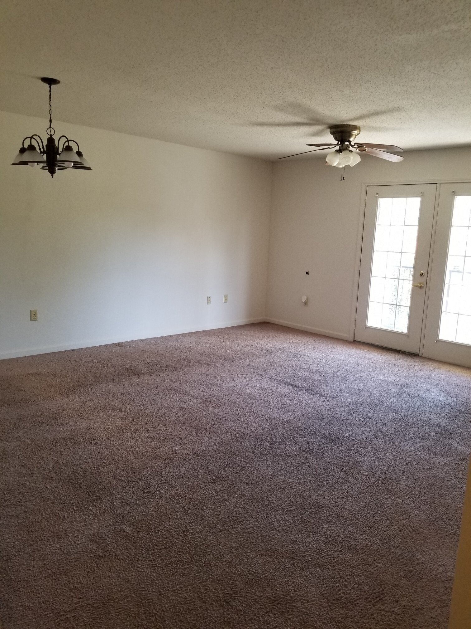 an empty living room with a ceiling fan