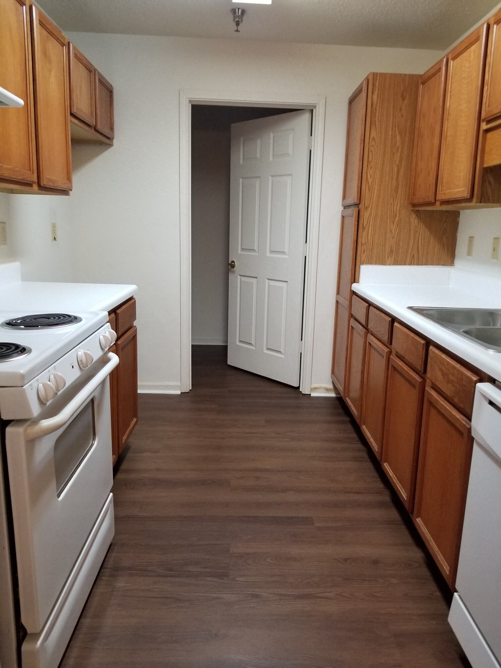 a kitchen with white appliances and wooden cabinets   and a door