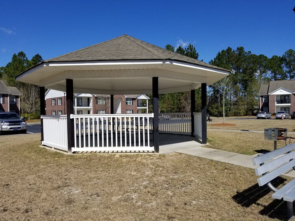 a gazebo with a white fence and a picnic table