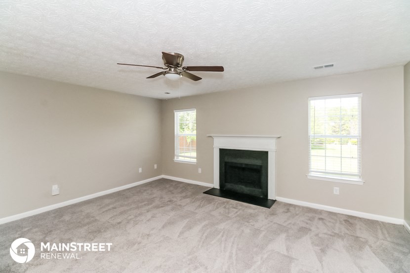 a living room with a fireplace and a ceiling fan