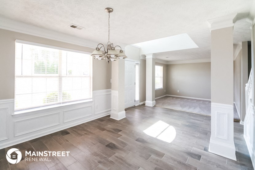 an empty living room with a large window and a chandelier