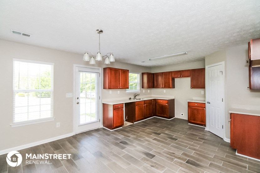 a kitchen with wooden cabinets and a door to a yard