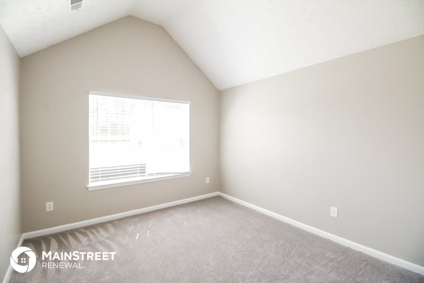 the upstairs bedroom with a large window and carpeting