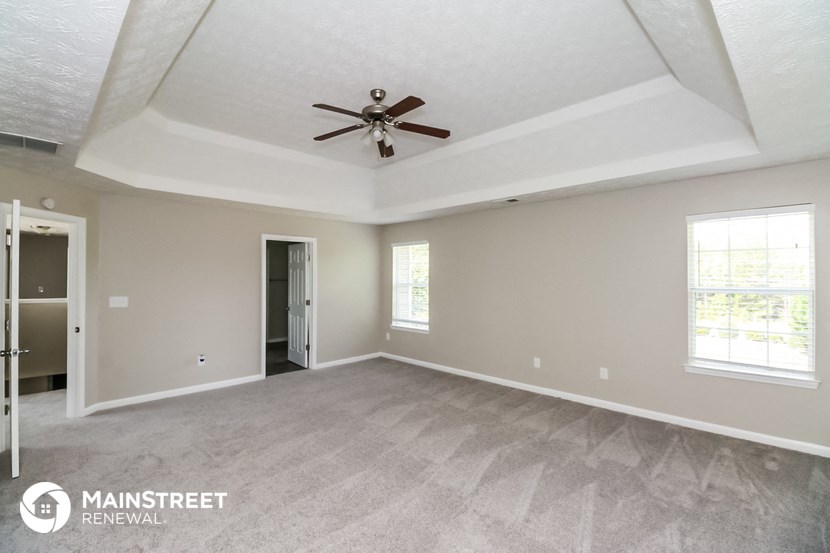 the living room of an empty house with a ceiling fan