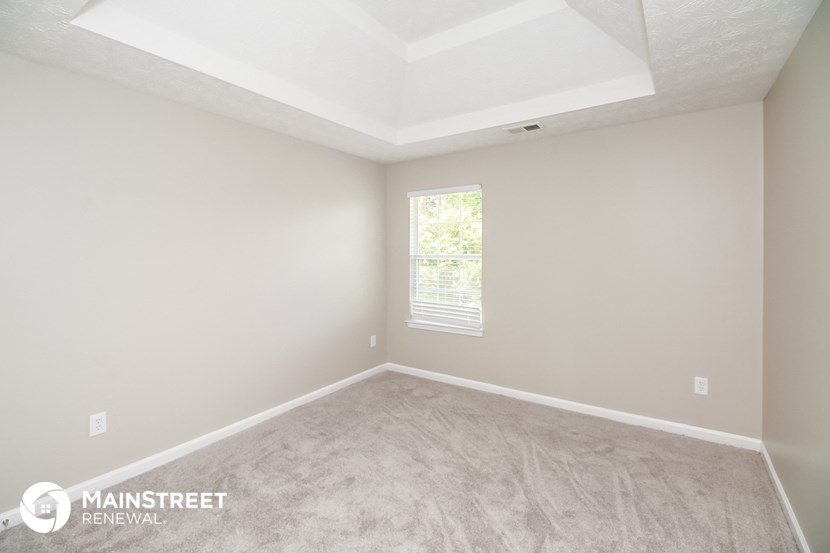the living room of a new home with carpet and a window