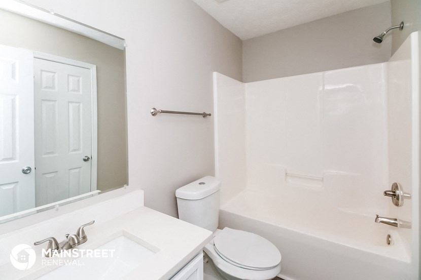 a white bathroom with a white toilet and tub and a sink