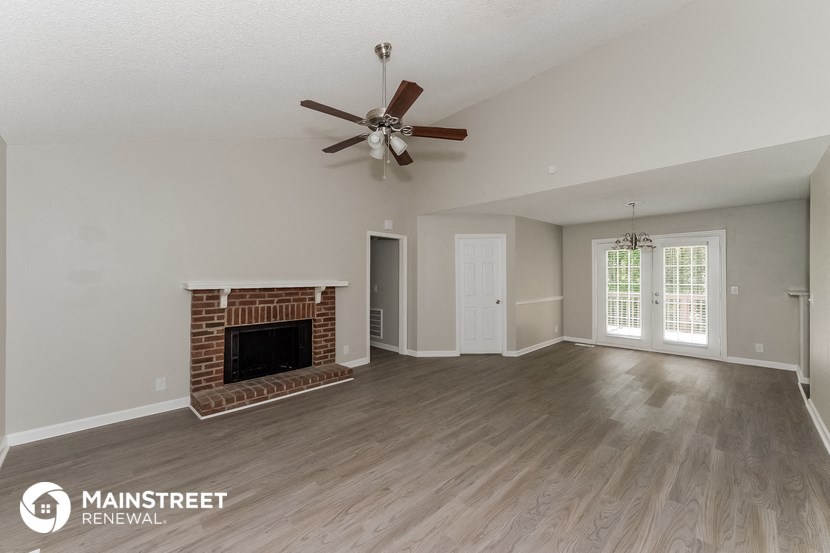 a living room with a fireplace and a ceiling fan
