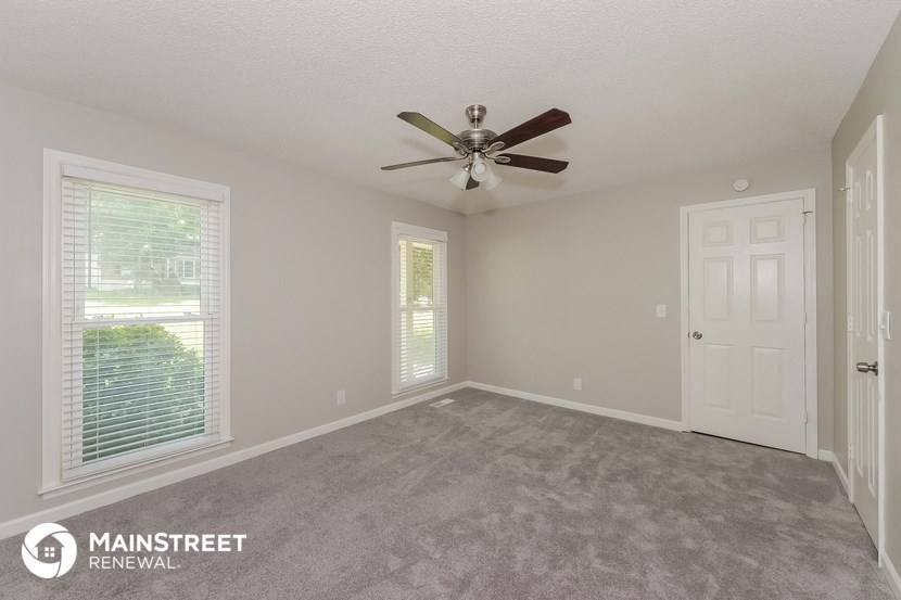 the spacious living room with ceiling fan and window