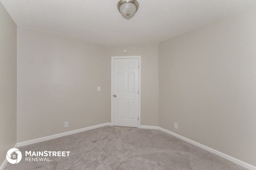 a bedroom with a white door and a carpeted floor