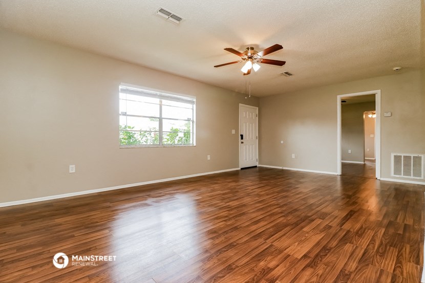 an empty living room with wood floors and a ceiling fan