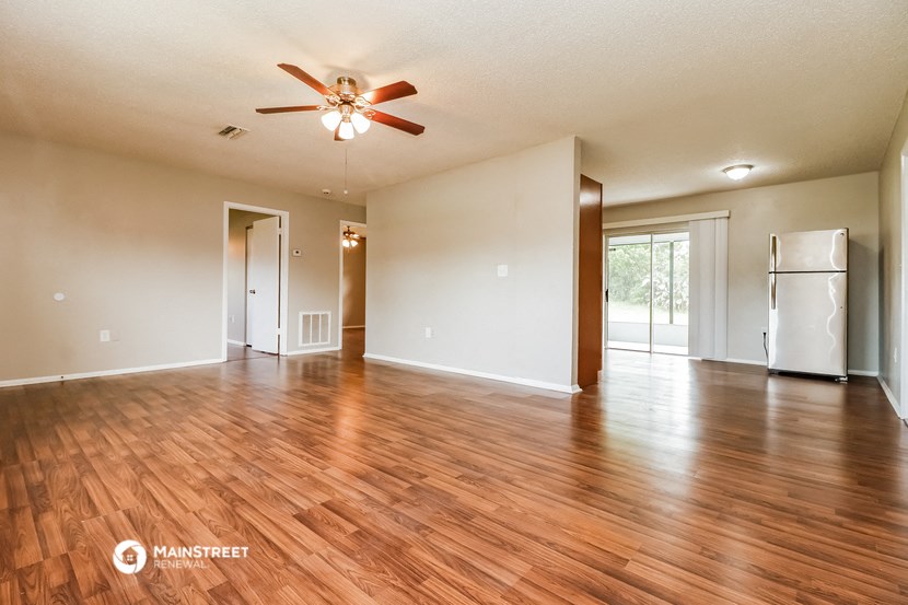 an empty living room with wood flooring and a ceiling fan