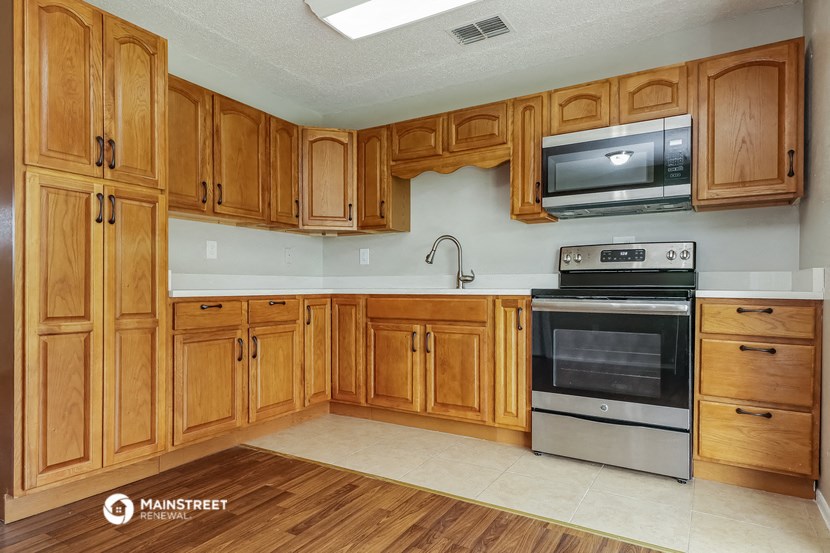 a kitchen with wooden cabinets and a stove and microwave