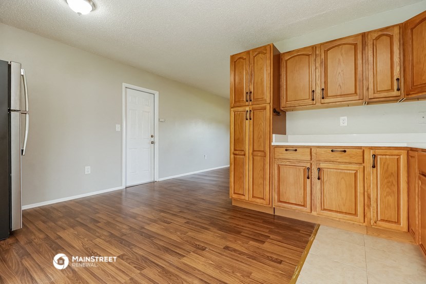 an empty kitchen with wooden cabinets and a refrigerator