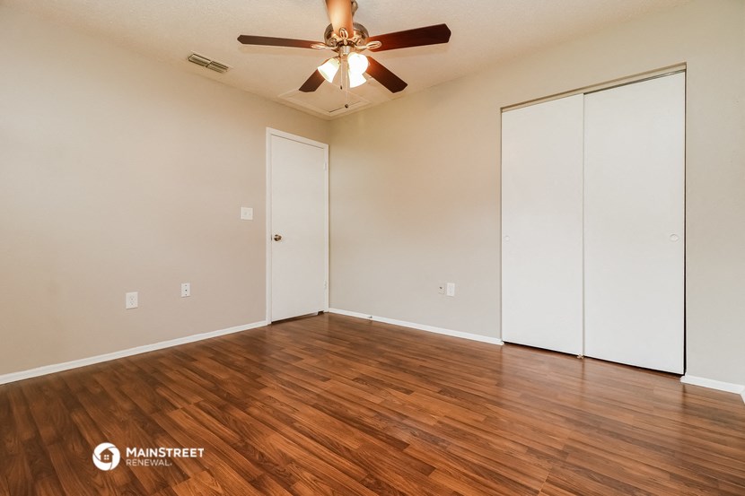 the spacious living room with wood flooring and a ceiling fan