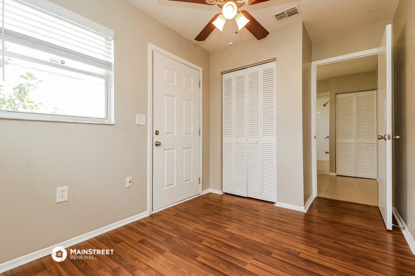 an empty living room with wood flooring and a ceiling fan