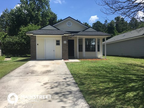 a small brick house with a driveway and lawn