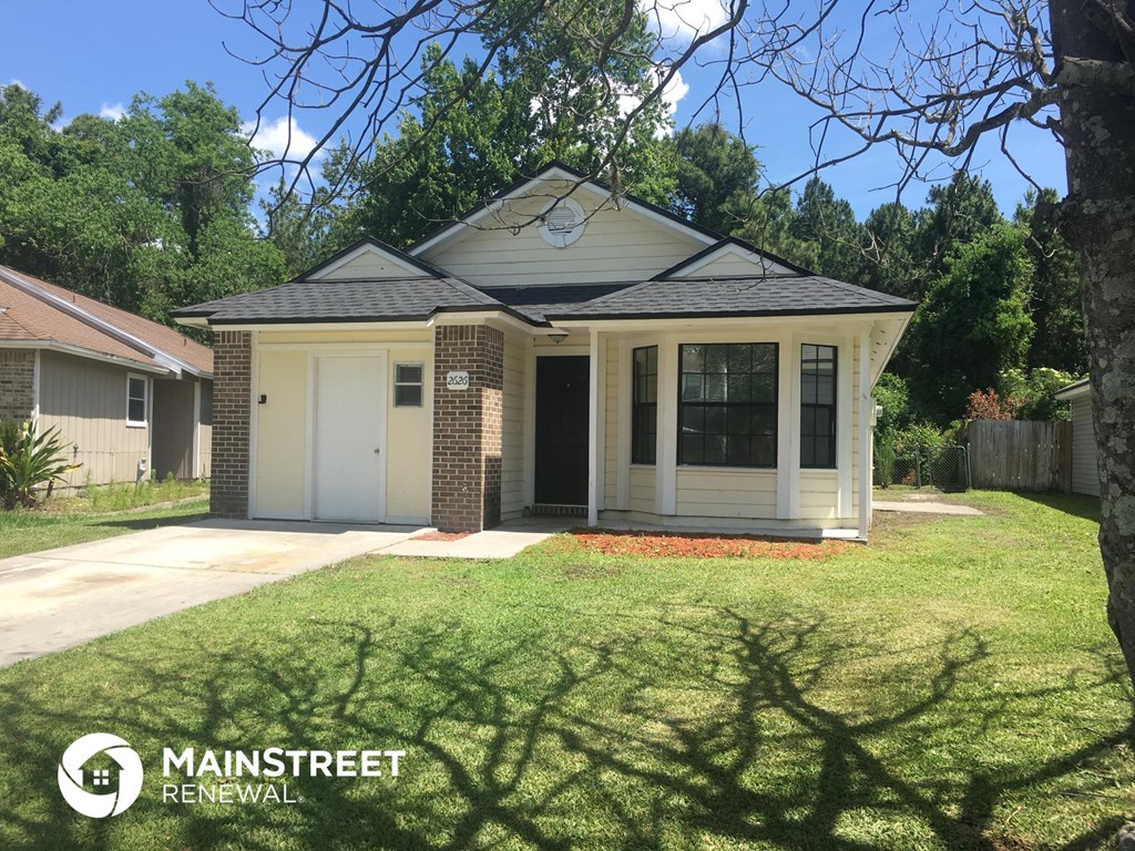 a small bungalow with a lawn and a garage