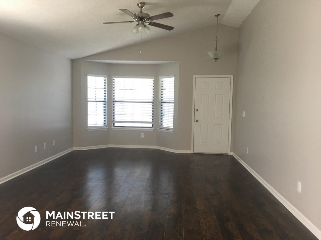 an empty living room with wood floors and a ceiling fan