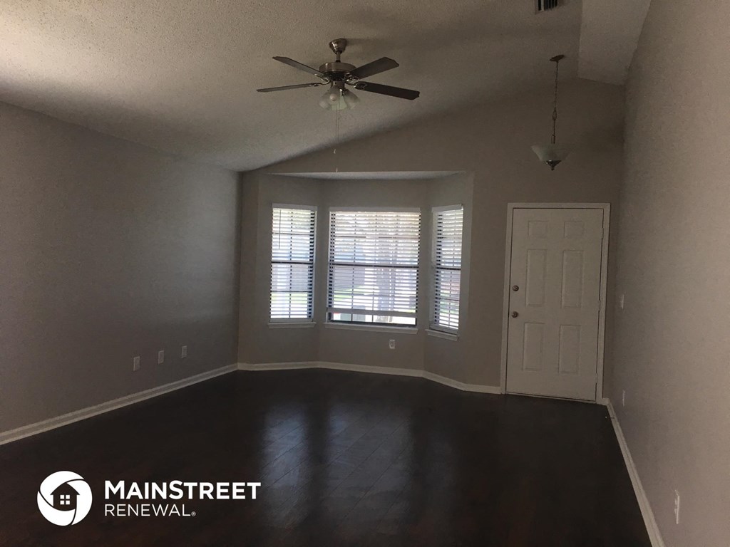 an empty living room with a ceiling fan and a window