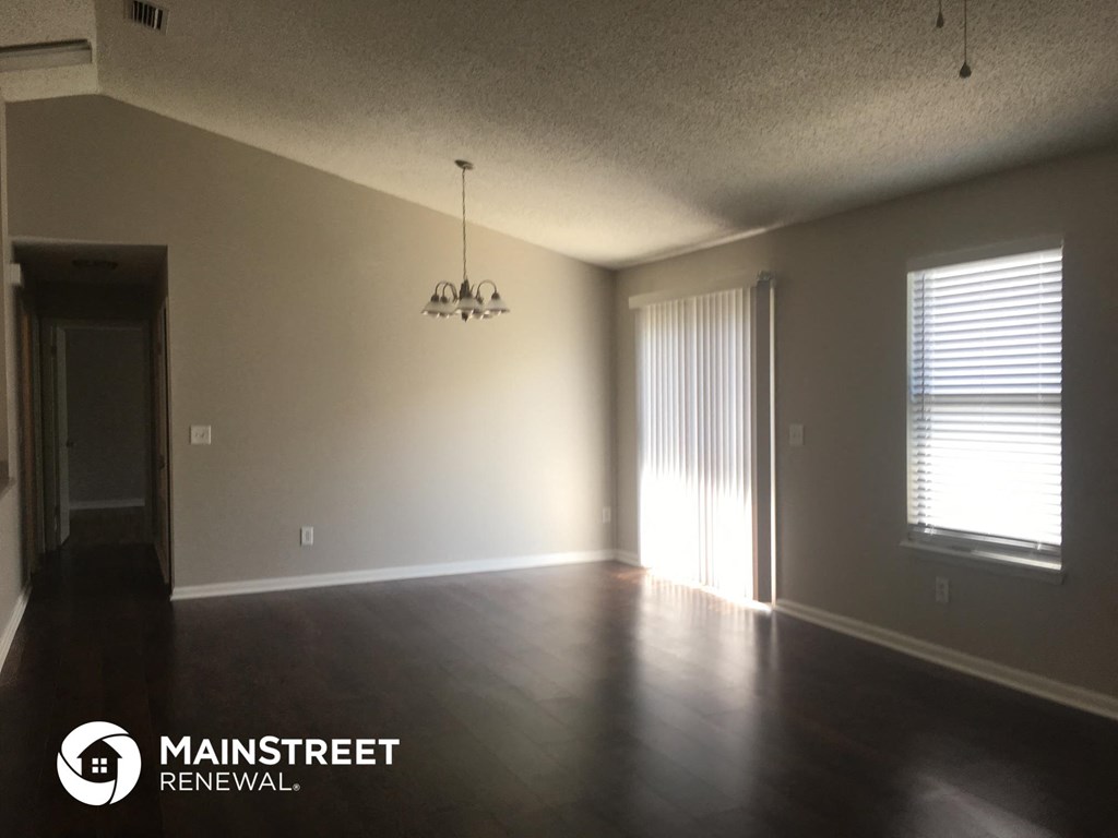 an empty living room with wood floors and a window