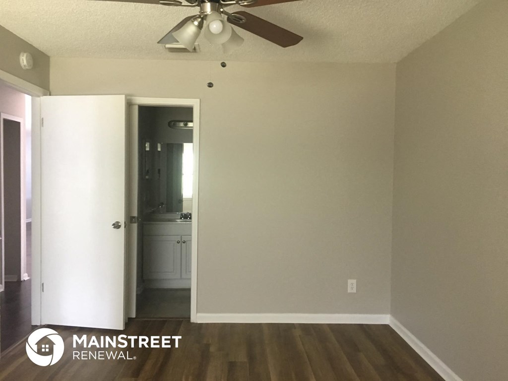 an empty living room with a ceiling fan and white walls