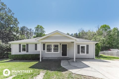 a small white house with a sidewalk in front of it