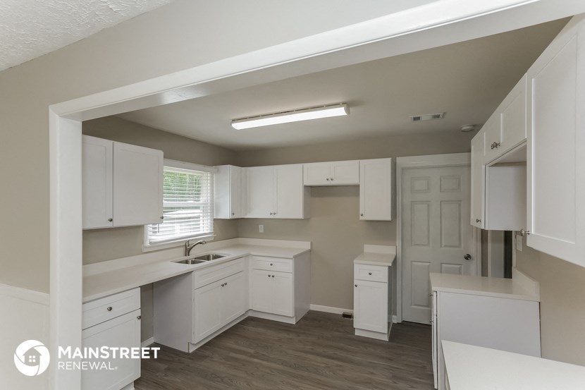 a kitchen with white cabinets and a sink and a window